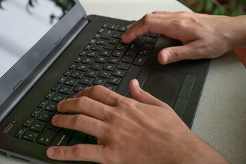 hands of a young man on the keyboard of a notebook
