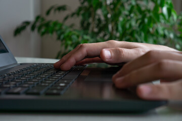 hands of a young man on the keyboard of a notebook