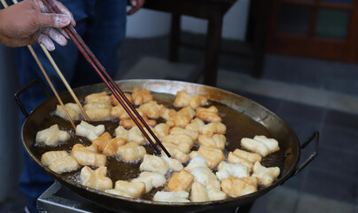 Closeup of fresh oriental dough, doughnuts frying in  hot oil pan.