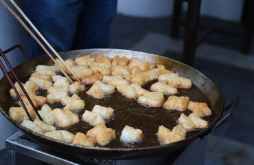 Closeup of fresh oriental dough, doughnuts frying in  hot oil pan.