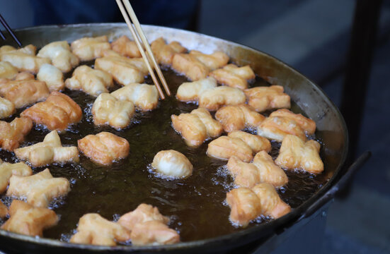 Closeup of fresh oriental dough, doughnuts frying in  hot oil pan.