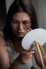 Domestic violence, abuse woman with bruise on face by the window looks in the mirror