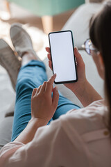 Woman hold mobile phone in hands, lying on sofa