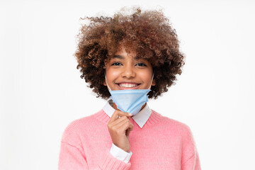 Portrait of smiling african american school girl taking off face mask after the end of pandemic....