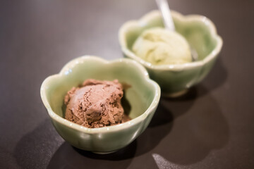 Ice cream scoops chocolate flavor in green cup and green tea flavor background