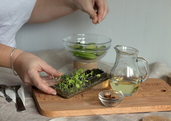 Girl preparing spring trendy green salad with olia and spices
