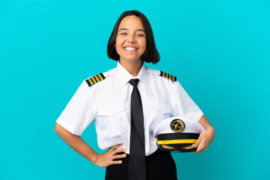 Young airplane pilot over isolated blue background keeping the arms crossed in frontal position