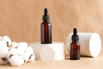 Creative still life with amber glass cosmetic bottles on a concrete podium against a background of kraft paper. Spa and skin care concept.