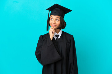 Young university graduate girl over isolated blue background and looking up