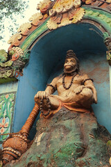 An old sculpture on the wall of a Hindu temple. Hanuman sits in the lotus position and chants the...