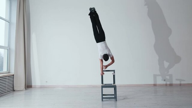 The acrobat keeps balance on the chairs. Acrobatic number without insurance