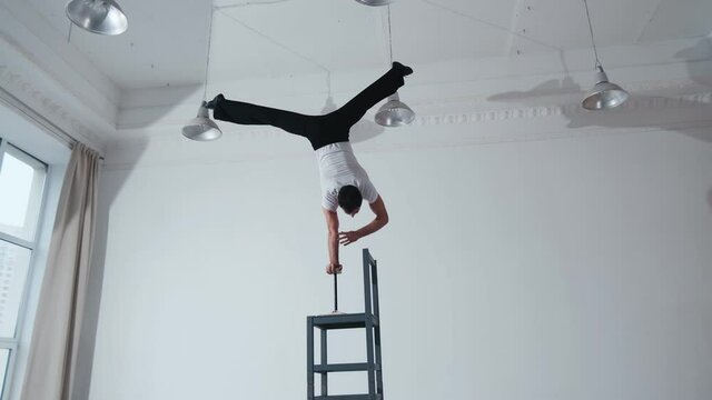 The acrobat keeps balance on the chairs. Acrobatic number without insurance