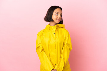 Young latin woman wearing a rainproof coat over isolated background . Portrait
