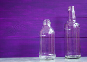 Glass transparent bottles on purple background
