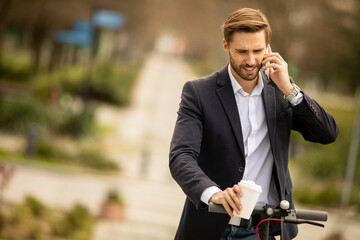 Young businessman using mobile phone  on electric scooter