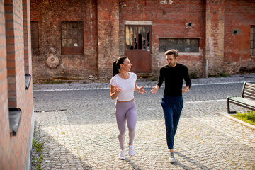 Young fitness couple running in urban area