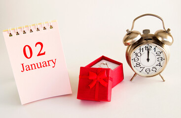 calendar date on light background with red gift box with ring and alarm clock with copy space. ...
