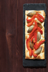 Traditional Spanish pizza coca on the shale board on brown background