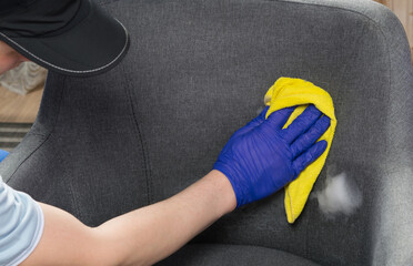 after cleaning the drapery of the chair with active foam, a hand in a protective glove, erases the excess, close-up