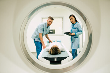Professional Doctor Radiologist In Medical Laboratory Controls magnetic resonance imaging or computed tomography or PET Scan with Female Patient Undergoing Procedure. - obrazy, fototapety, plakaty