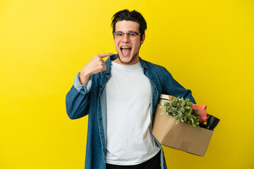 Russian Man making a move while picking up a box full of things isolated on yellow background...