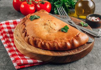 Italian food, closed pizza calzone with cheese, gray stone background.