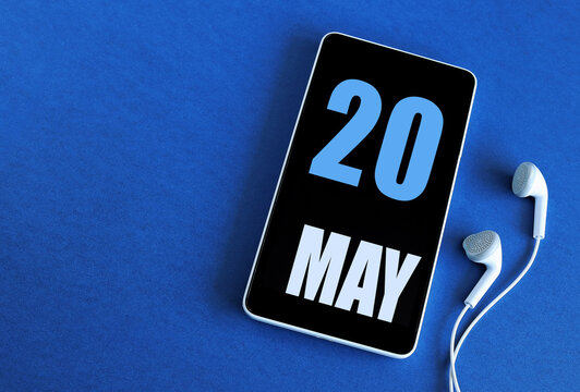 May 20. 20 st day of the month, calendar date. Smartphone and white headphones on a blue background. Place for your text. Springtime month, day of the year concept