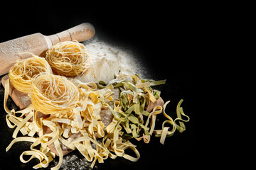 Freshly cooked pasta is lying on a dark surface dusted with flour. Italian pasta. Tagliatelle. Raw pasta. Italian pasta recipe. Top view, copy space