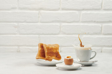 Coffee splash from a cup with breakfast on white table