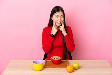 Young Chinese girl  having breakfast in a table smiling with a happy and pleasant expression