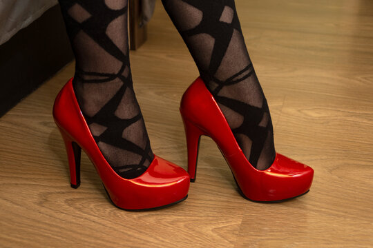 Legs of woman in red high heeled shoes and black tights with a pattern