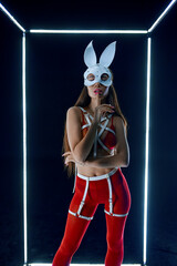 Fototapeta na wymiar Stripper in rabbit mask dancing in luminous cube