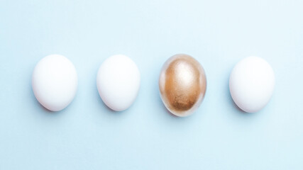 Easter background blue. Golden, white colour egg on pastel blue background in Happy Easter decoration. Flat lay, top view.