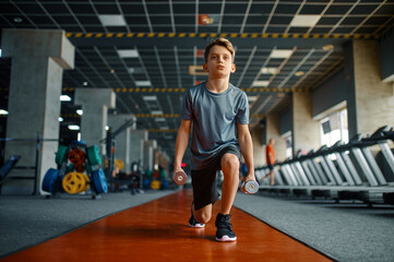 Obraz na płótnie Canvas Boy doing exercise with dumbbells in gym