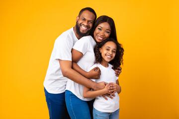 African American man hugging his wife and smiling daughter