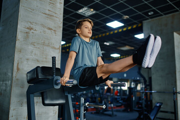 Youngster doing ABS exercise on machine in gym