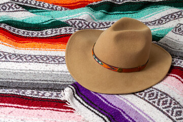 A cowboy hat on a colorful Southwestern design blanket in the background