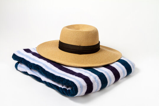 A large brown brim on a striped beach towel with a white background