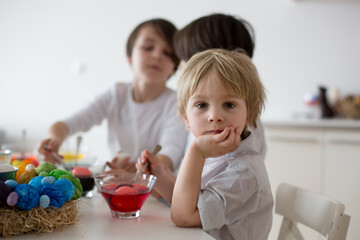 Obraz na płótnie Canvas Children, boy siblings, coloring eggs for Easter