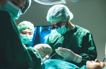 Surgeon doctor is wearing surgical gloves before the surgery in operating room.Asian doctor and an assistant in the operating room for surgical venous.