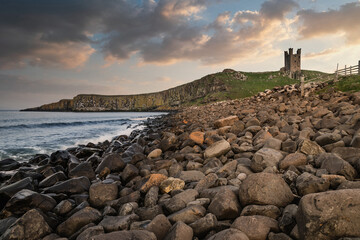 Landscape image of Dunstanburgh Castle on Northumberland coastline in England during late Spring...