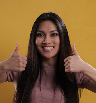 Young pretty woman makes thumb-up gesture - studio photography