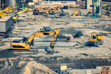 Construction site with heavy machines in the urban populated area.