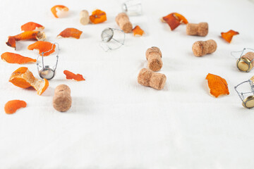 Champagne corks and dried tangerine skins lie on a white tablecloth. The end of the holiday