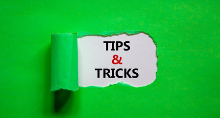 Tips and tricks symbol. Words 'Tips and tricks' appearing behind torn green paper. Beautiful green background. Business, Tips and tricks concept. Copy space.
