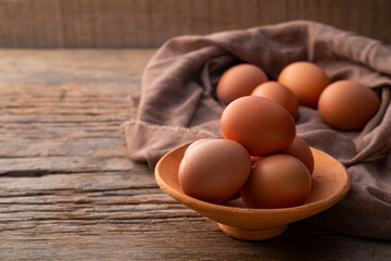 Chicken eggs in Clay bowl on old wood table background