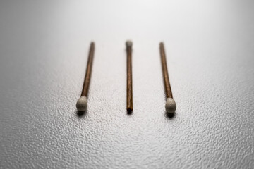 Three brown and white matches. White background, some matchbooks. Wooden matchsticks