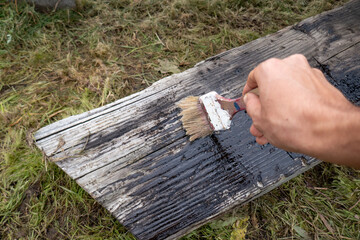 Old and ruined wooden bench treated with oil and primer. Hand painting with a brush