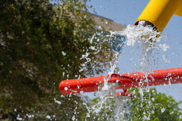 Summertime fun for the kids at the splash pad to play with water falling from bright colored yellow fountain to pool below.
