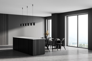 Grey kitchen interior with cutting table and chairs near window, concrete floor